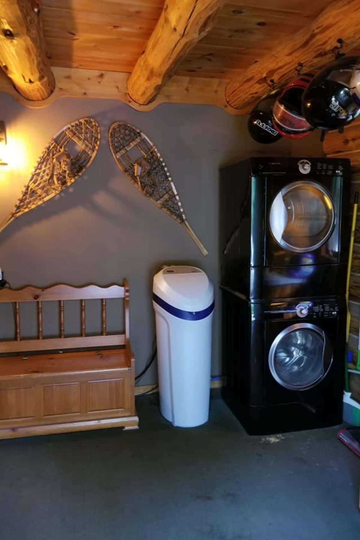 stacking black washer and dryer on wall under helmets and snow shoes