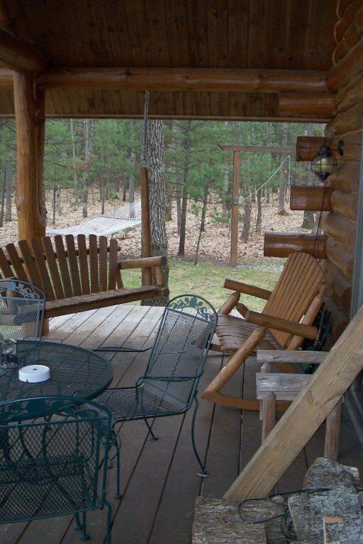 porch with rocking chairs and metal table in front of log cabin