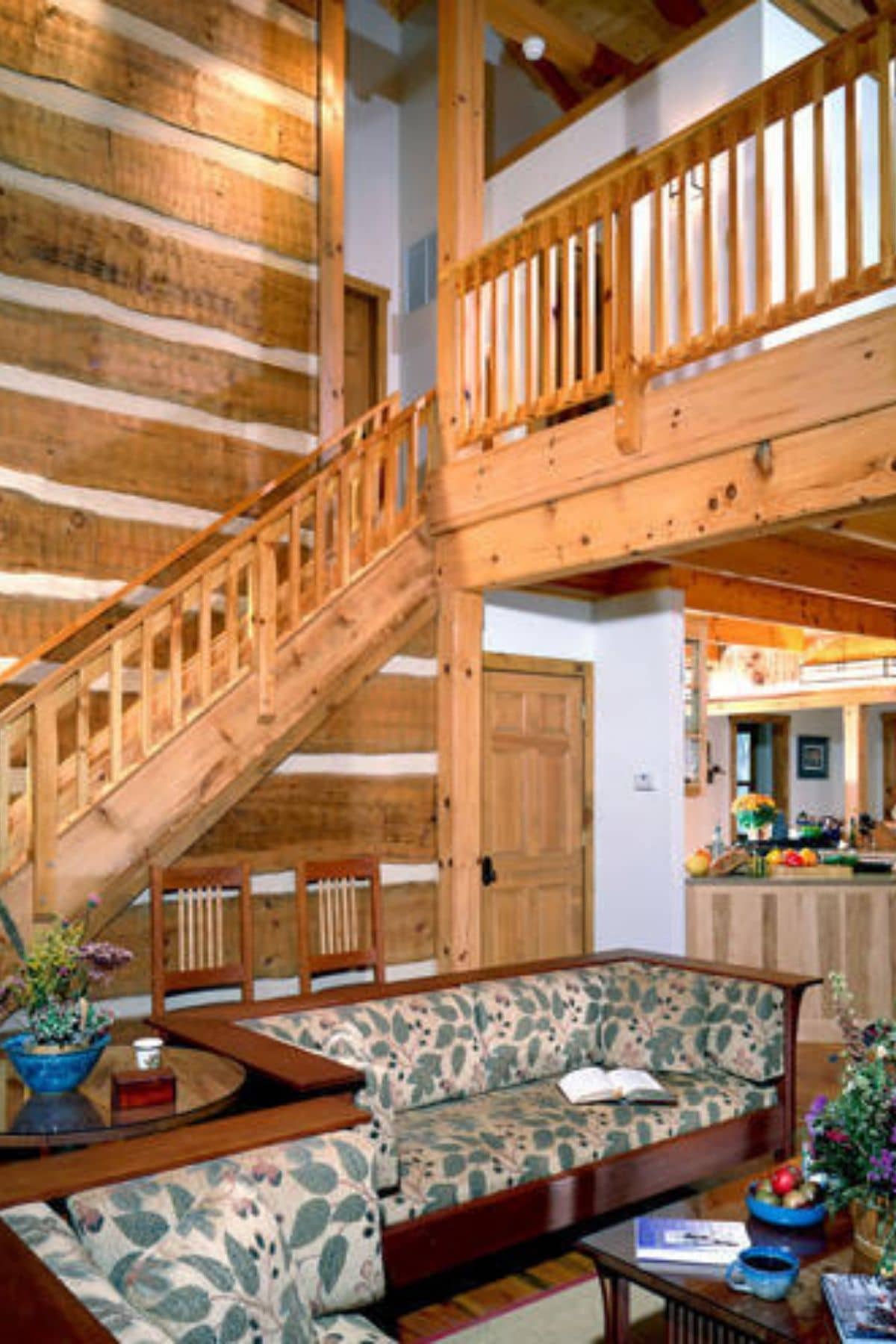stairs to loft behind sofa against wood log cabin wall