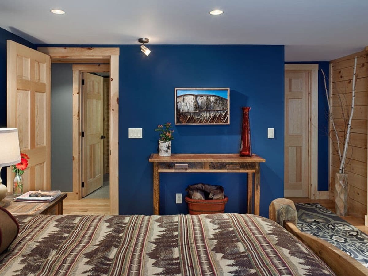 blue wall in bedroom of log cabin with rustic bedding in foreground