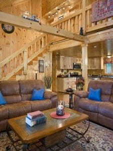 brown sofas with blue pillows in log cabin living room