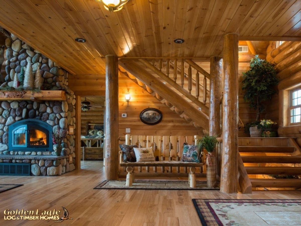 wooden bench beside wall in front of stairs to second floor of log cabin