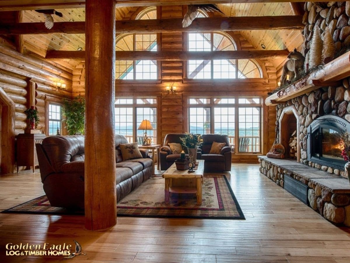 view into great room of log cabin with fireplace on right and sofa on left