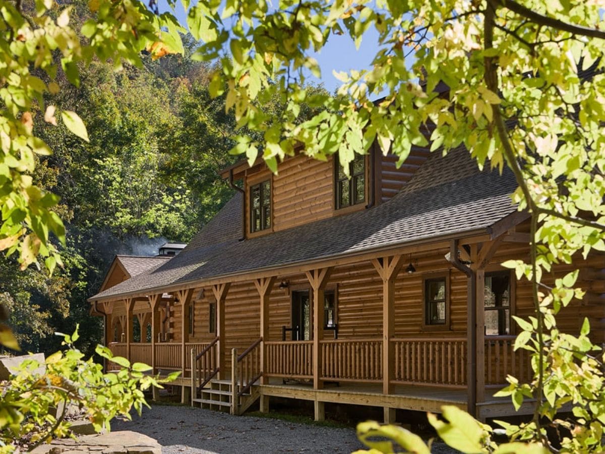 front porch of log home behind leaves of tree