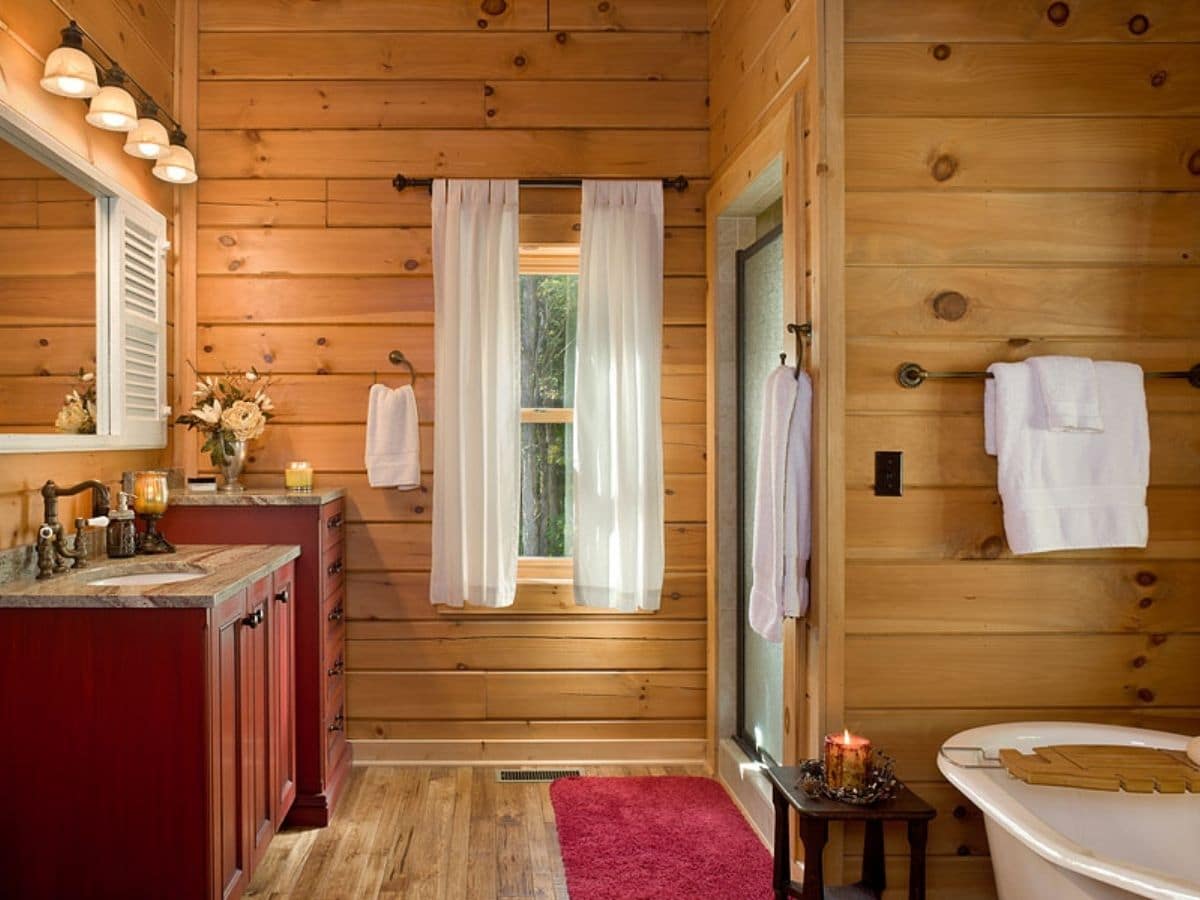 red cabinets on left in bathroom across from shower with bathtub in foreground