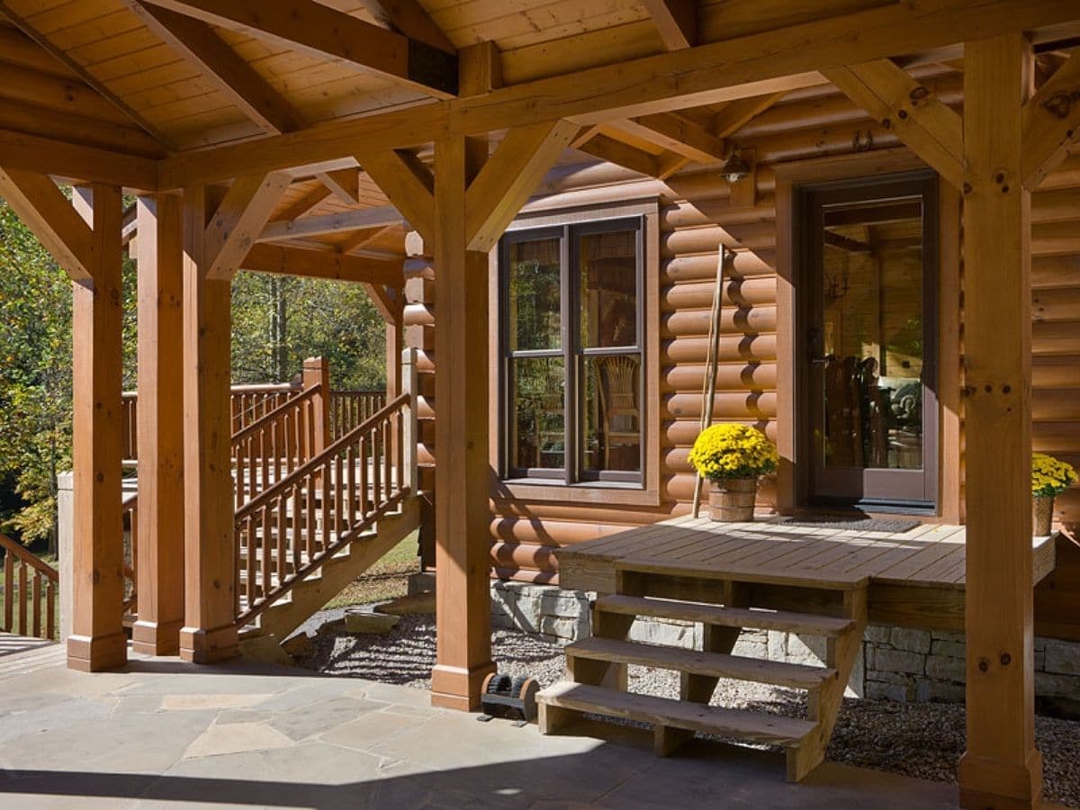 side of log cabin with deck and porch leading into kitchen