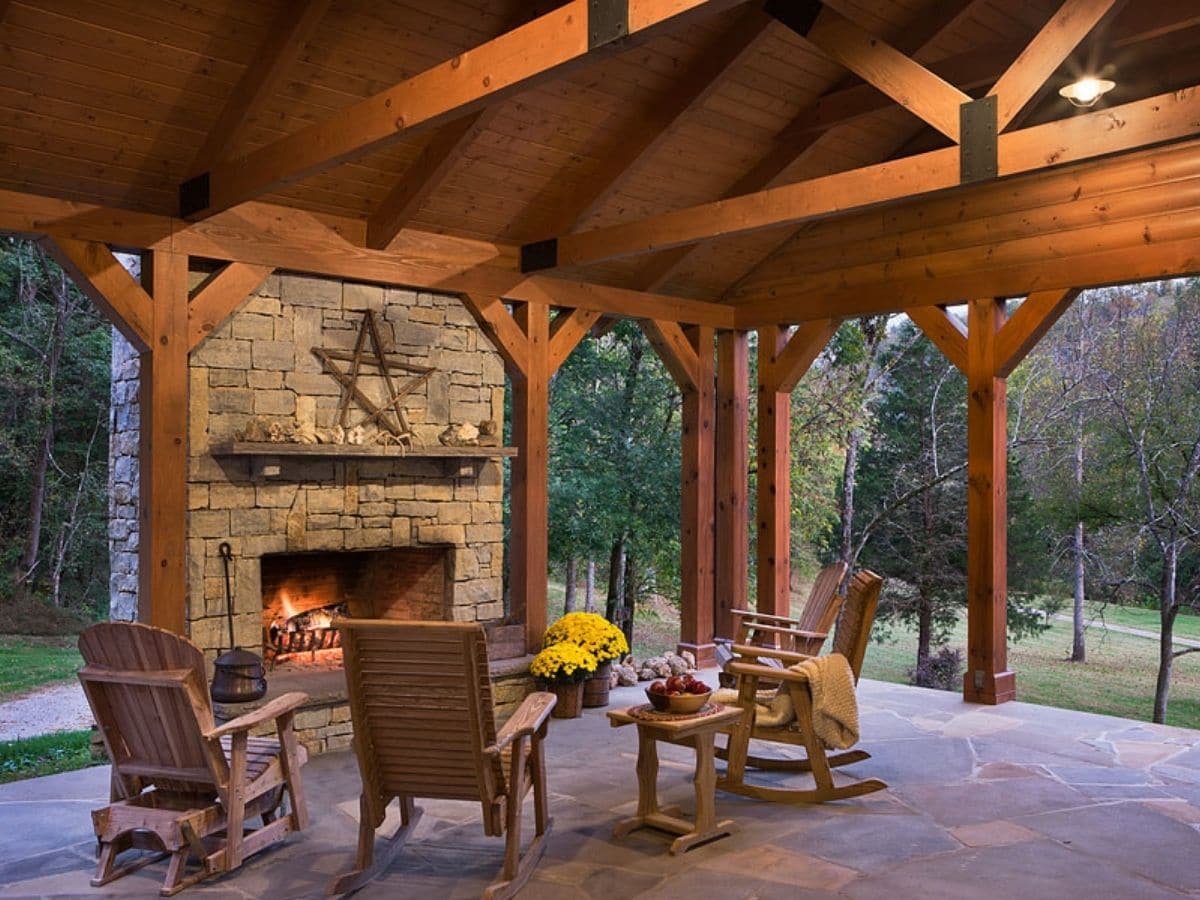 rocking chairs and table outside log cabin on deck with fireplace
