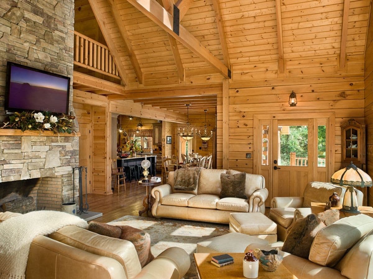 tan sofa and chairs next to fireplace in log home