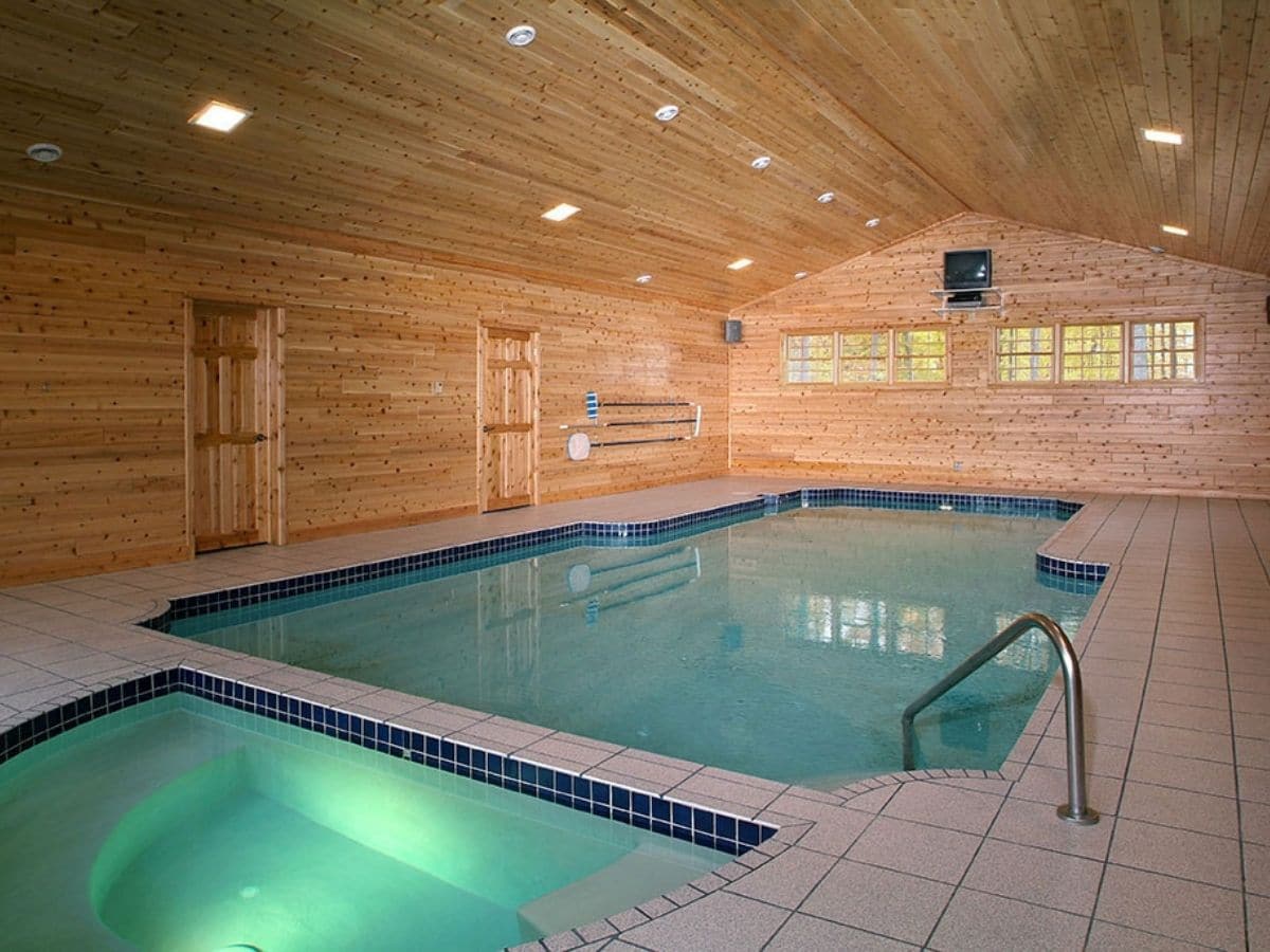 pool and hot tub in large room with wood paneling