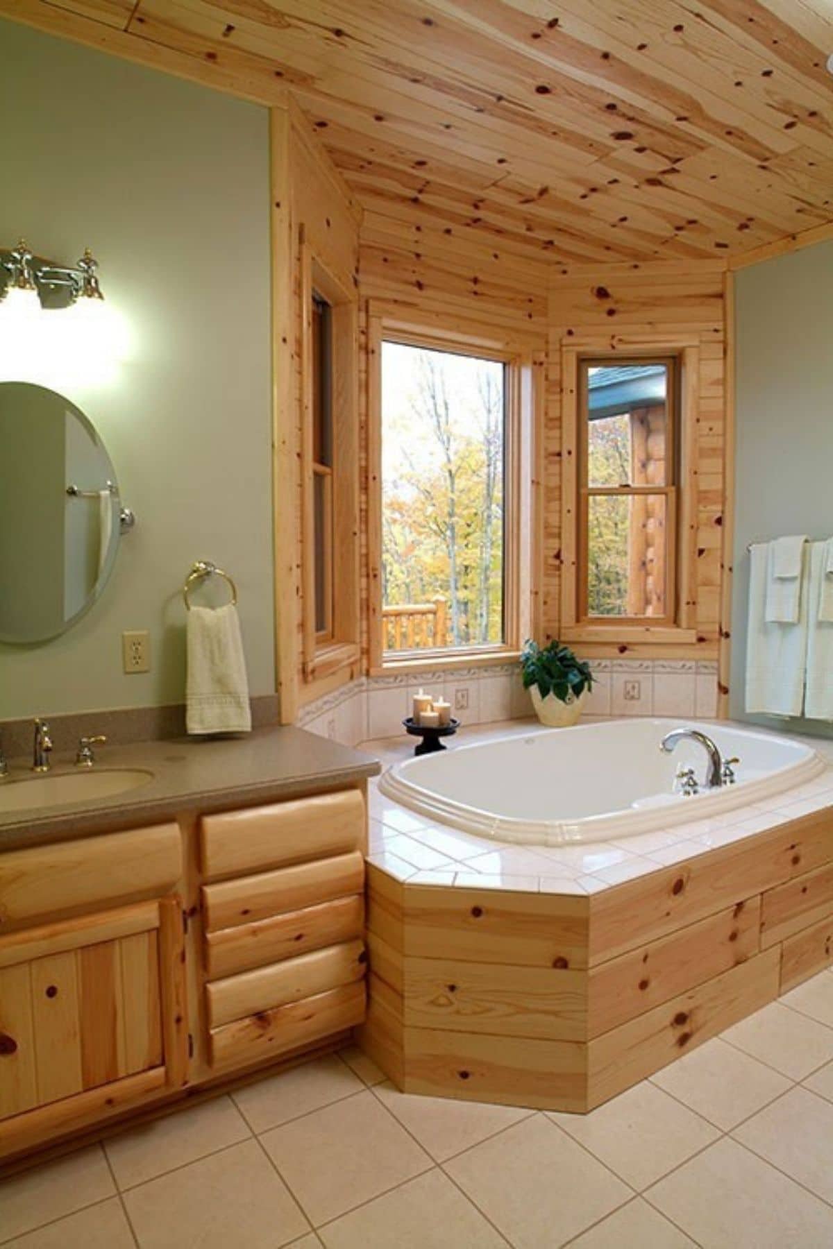 bathroom with light green walls and jacuzzi tub surrounded by pine paneling