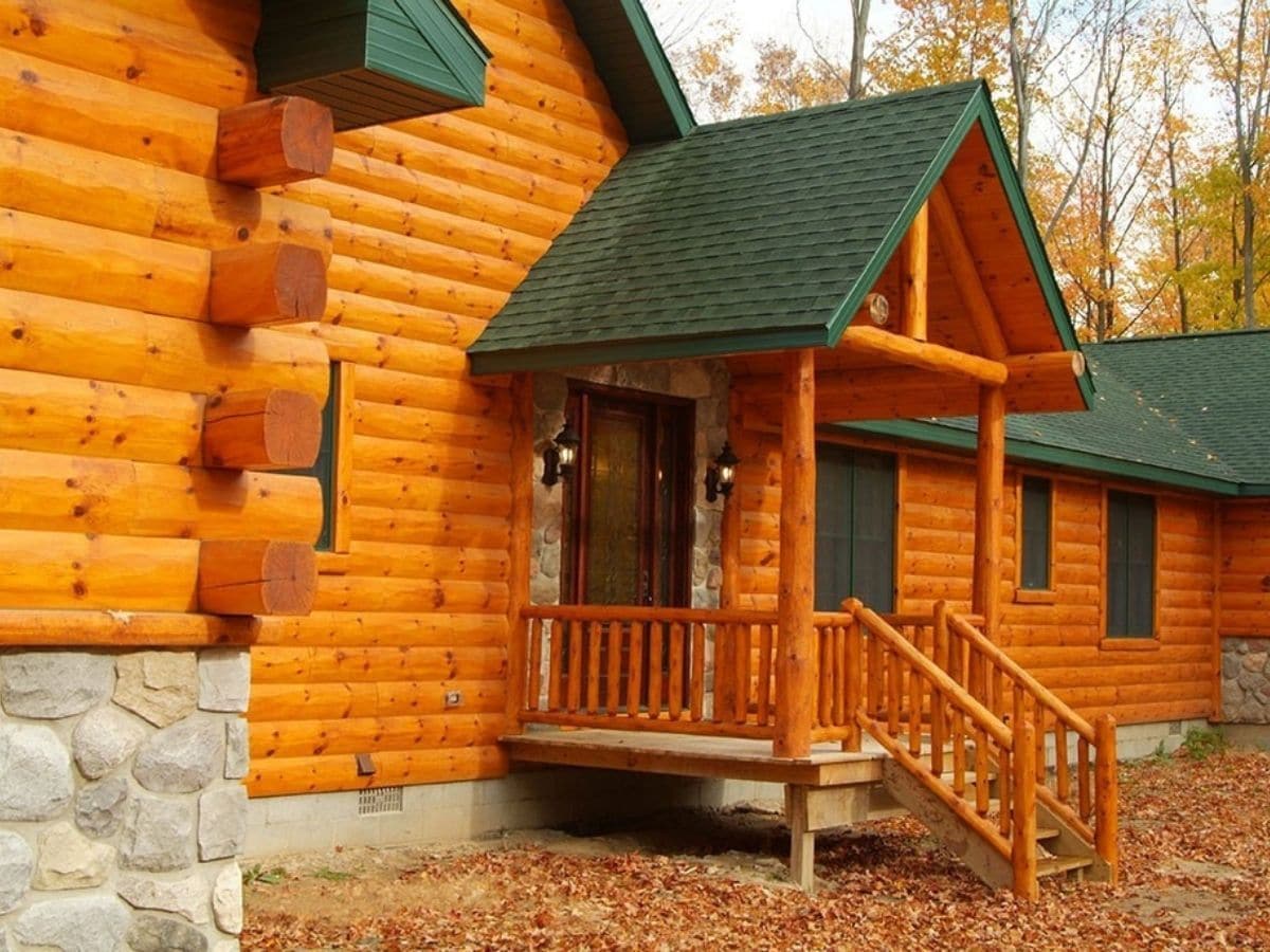 stained log siding with green roof and small porch by entry door
