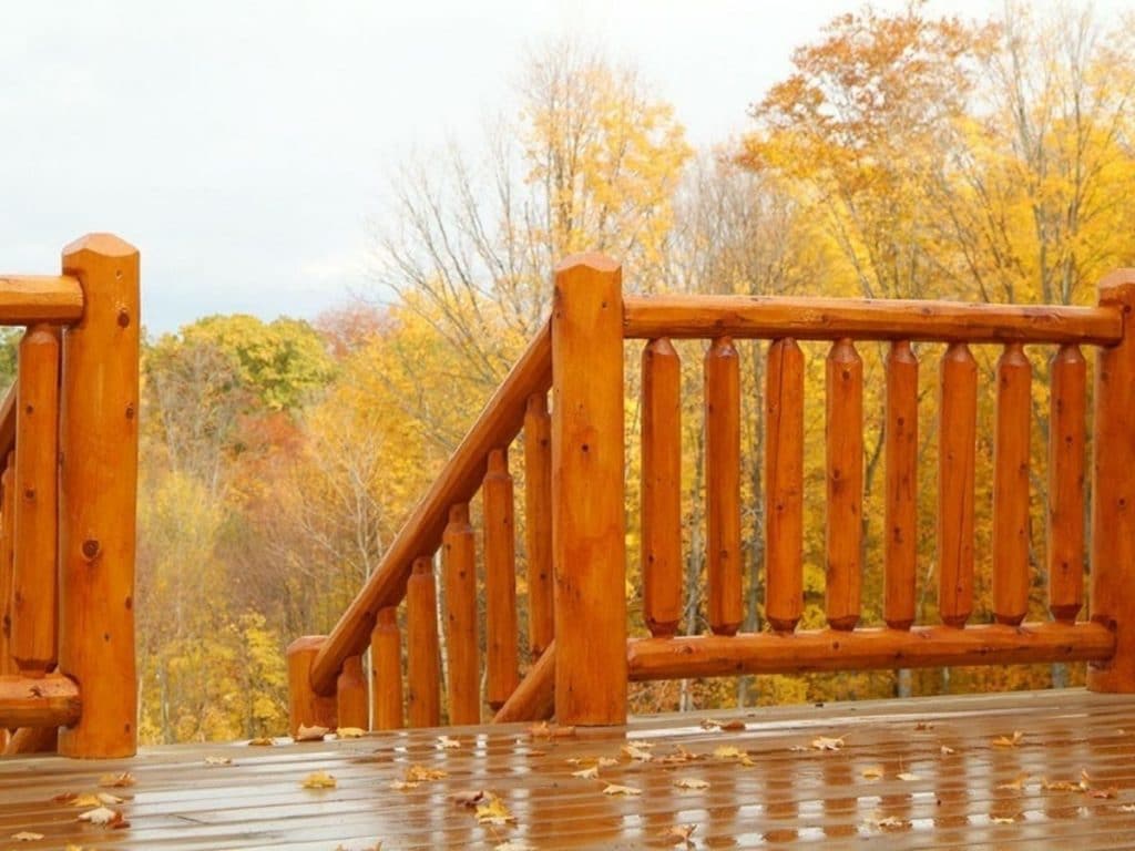 cedar railing on deck looking out over trees in valley