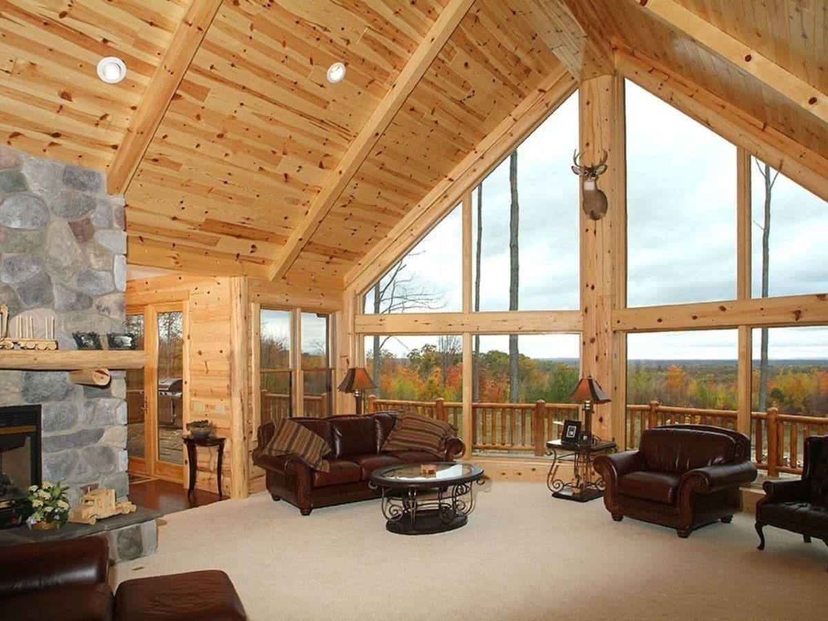 great room with brown sofas and floor to ceiling picture windows on back wall