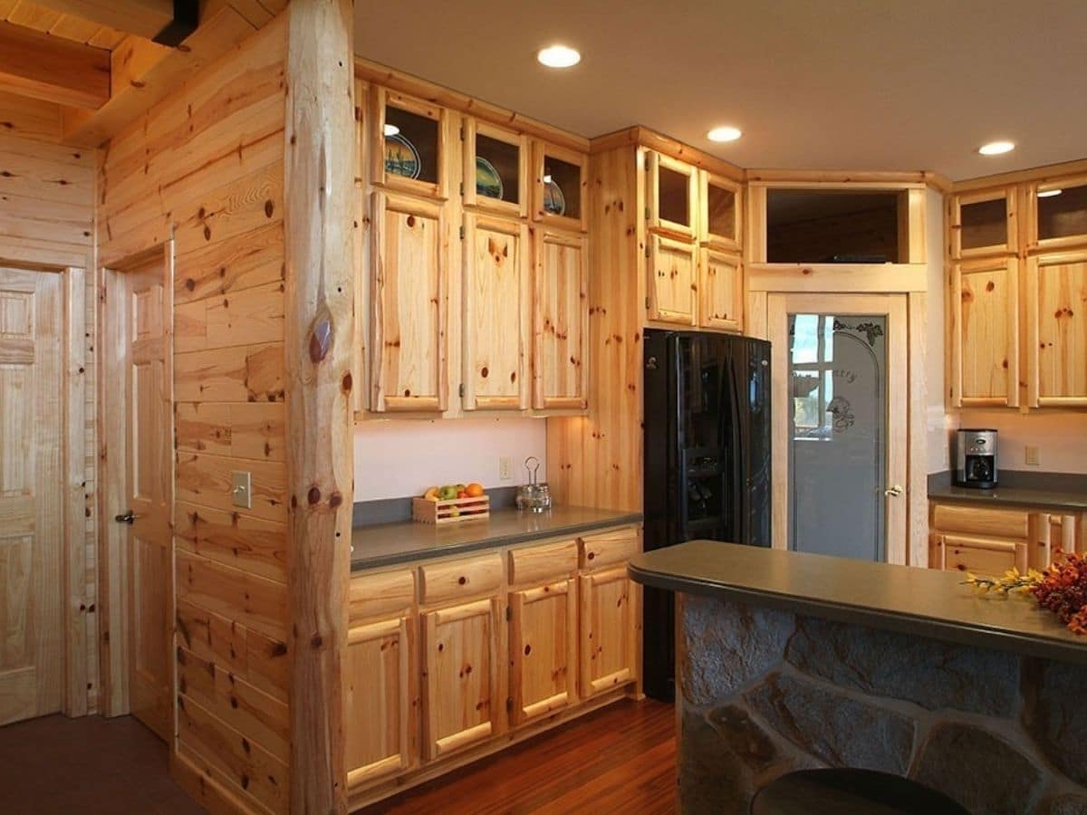 knotty pine cabinets next to black refrigerator in kitchen with island