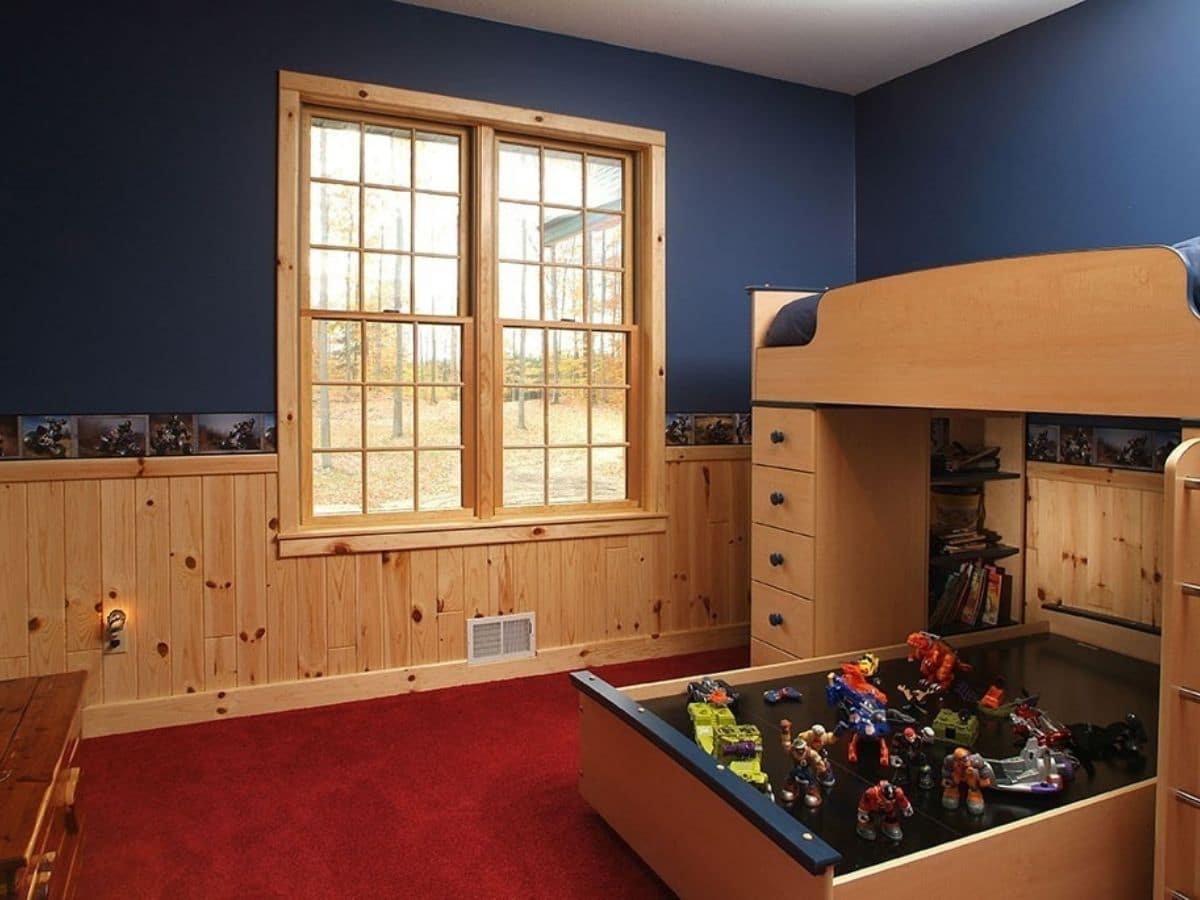 bedroom with pine wains cotting and blue paint around window with bunk bed on right