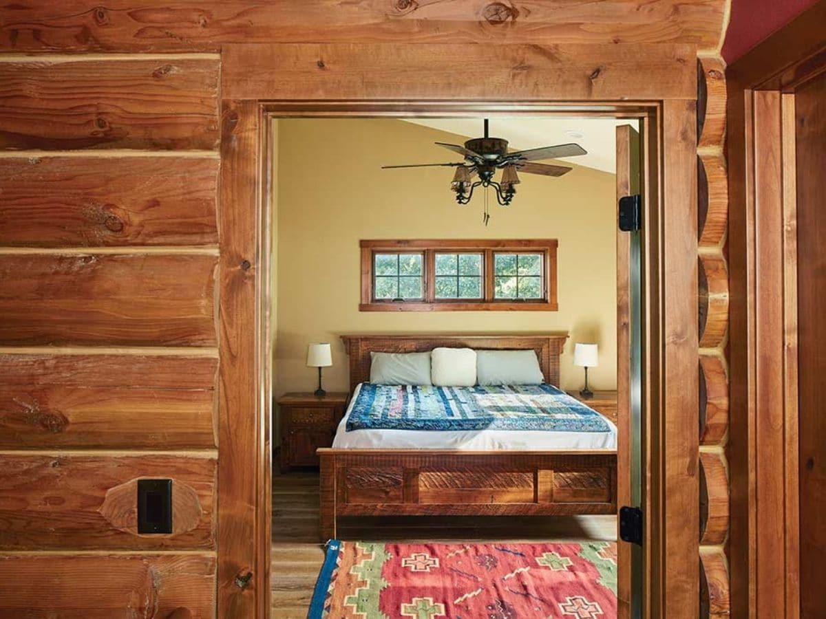 log cabin wall and entry to bedroom with wood bedrame