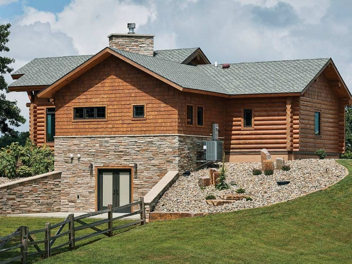 side of log cabin with stone bottom half and partial landscaped side