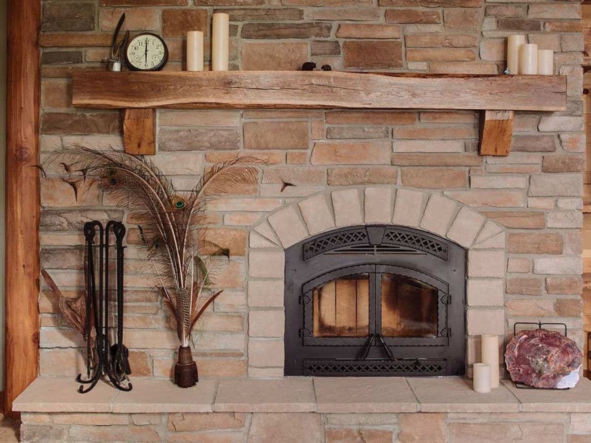 stone fireplace with black doors and wood mantle