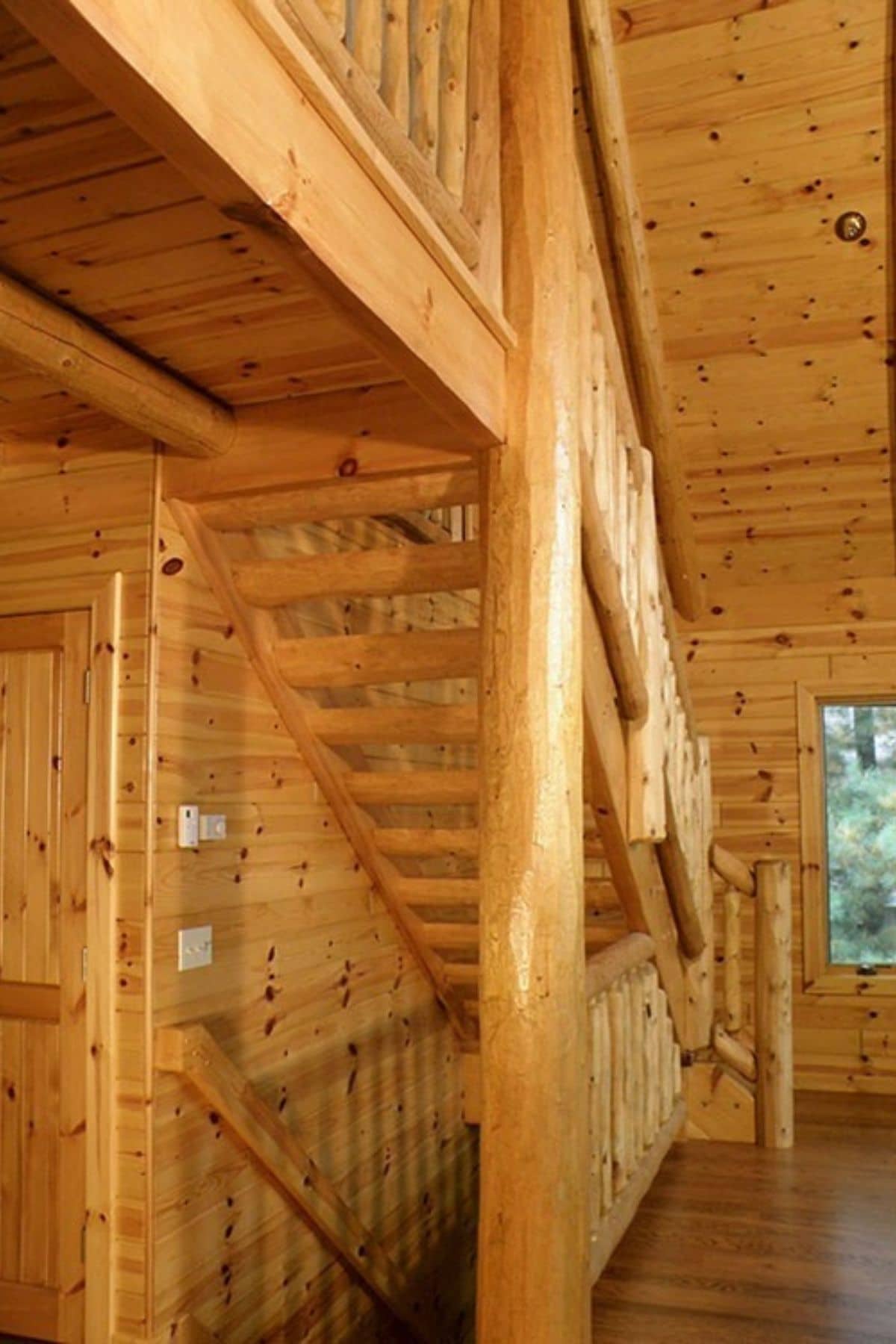 log stairs from second floor to main floor of log cabin against left of imge