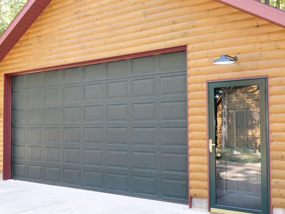 green garage door next to green door on side of log home