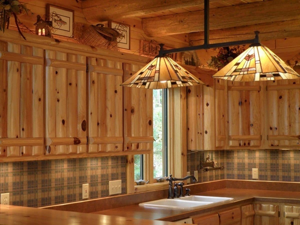 log cabin kitchen with tile backsplash and ornate fixtures in foreground