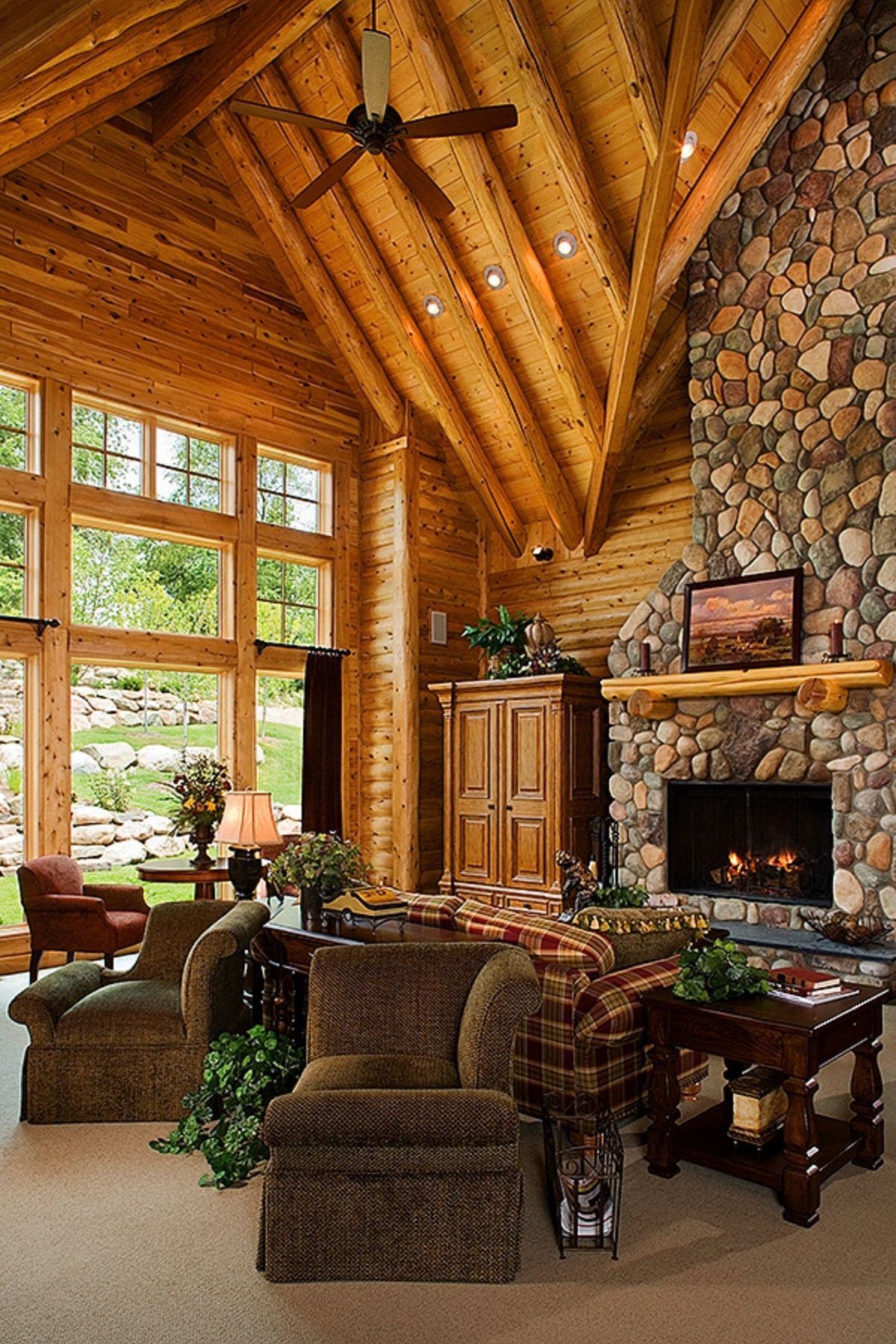 great room with stone fireplace in right backgound windows on left and dark brown chairs in center