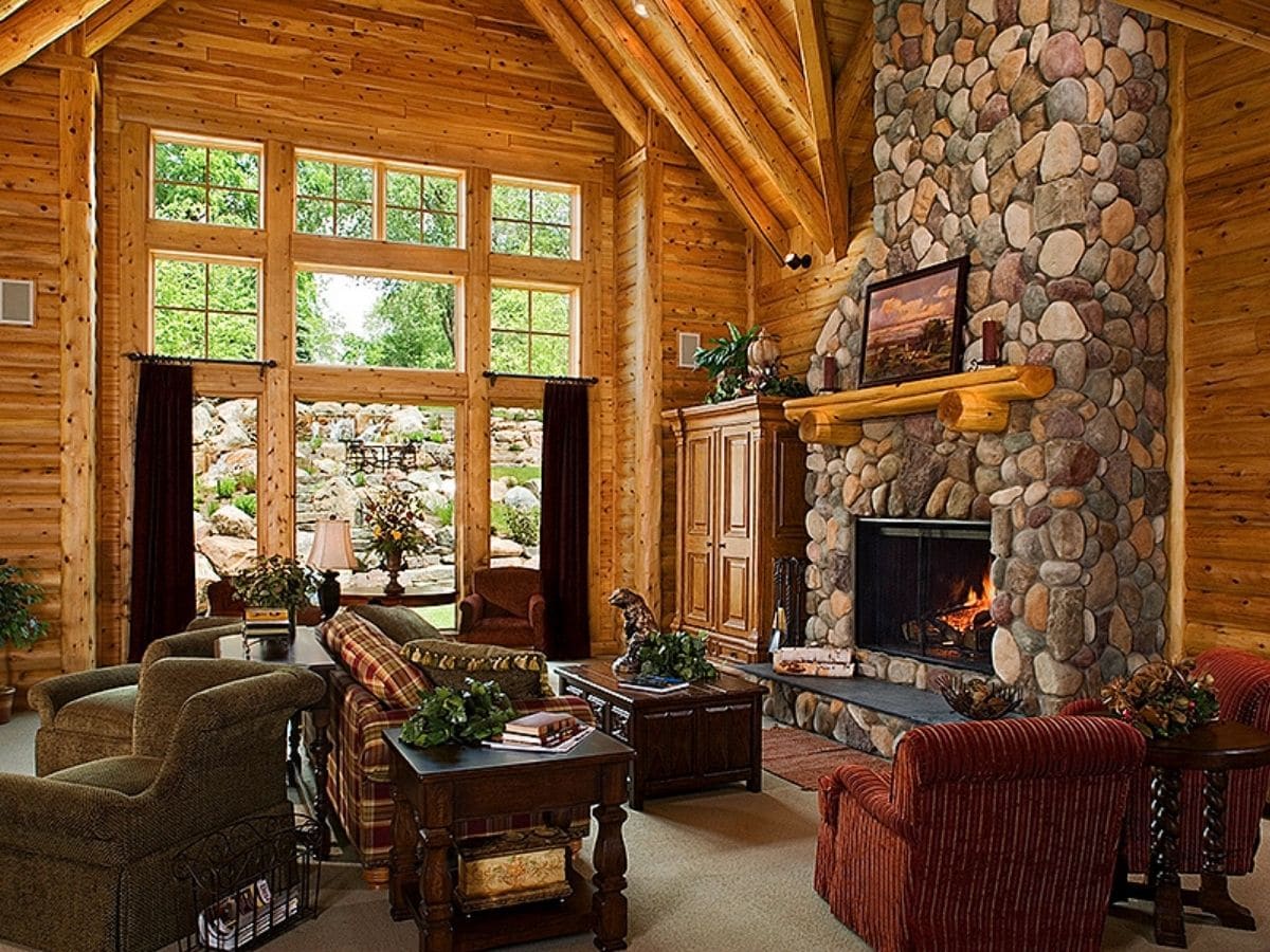stone fireplace on right of great room with sofas in front of wall of windows