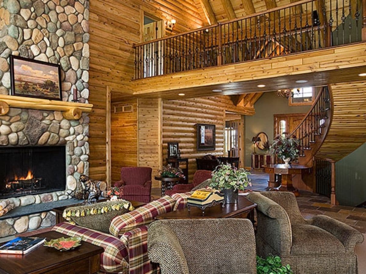 stone fireplace on left of image with sofas in foreground and loft landing above in upper right