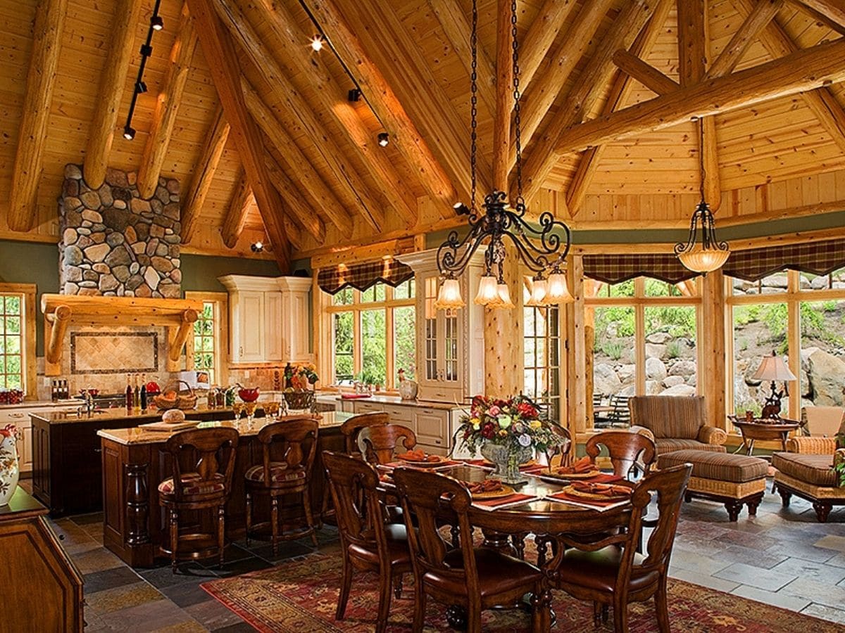 small dining table beside island in kitchen with log beams in ceiling