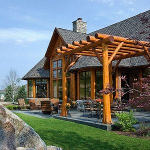 log cabin with wooden portico against back half of home