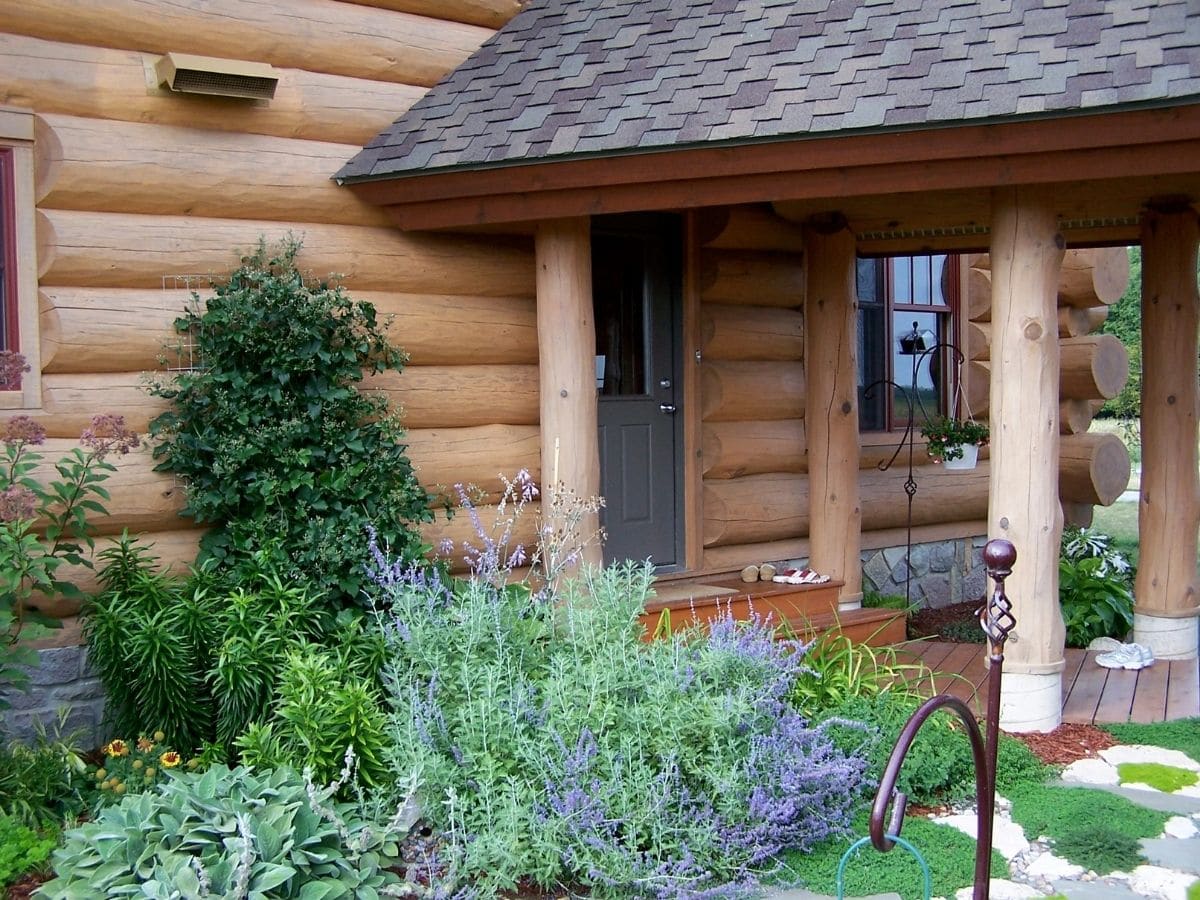 view of shrubs beside side door on log cabin with small awning