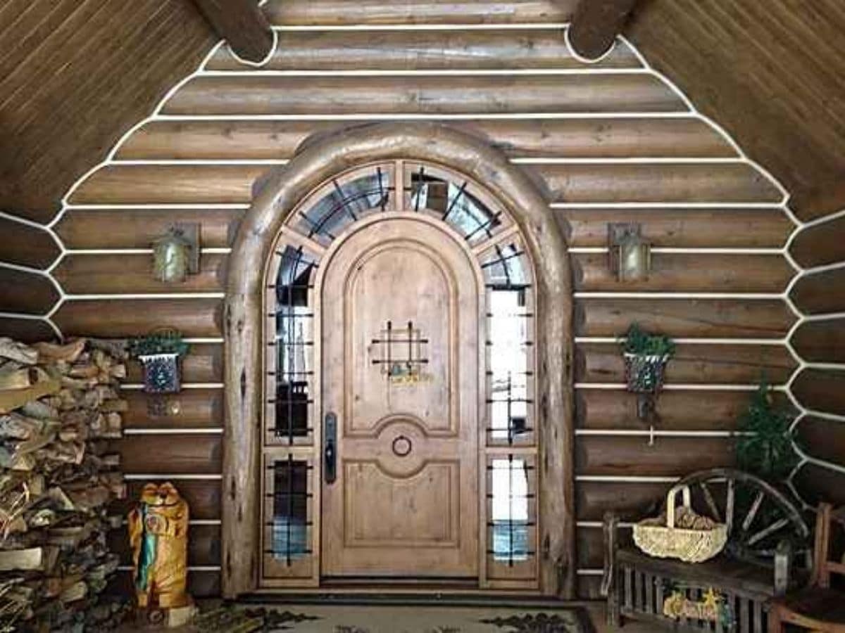 rustic front door with glass arch surround and log chicnk on sides