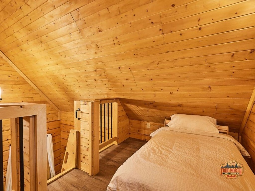 small bed in loft with angled log cabin roof
