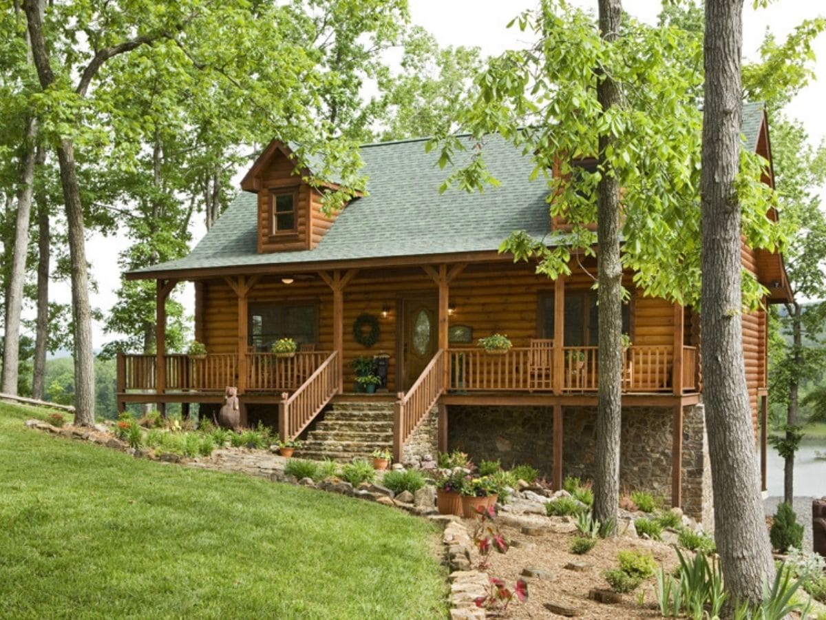 light wood log cabin with green roof and front porch