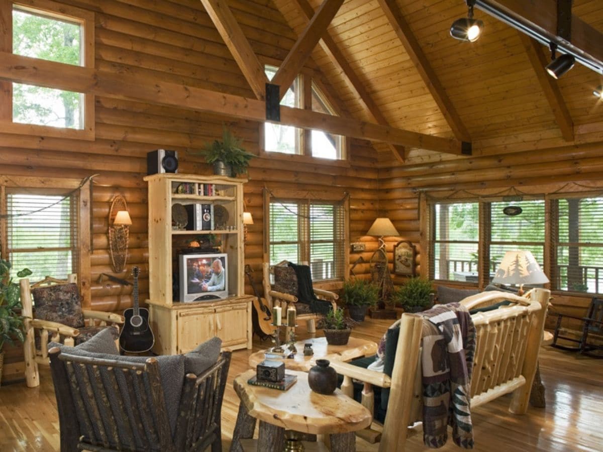 log cabin living room with wood furniture underneath log rafters