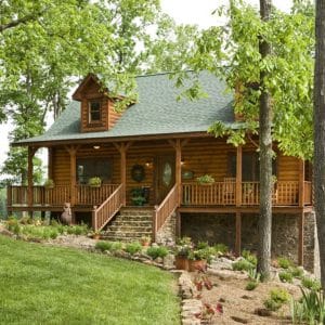 light wood log cabin with green roof and front porch