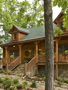 light wood log cabin with green roof and front porch