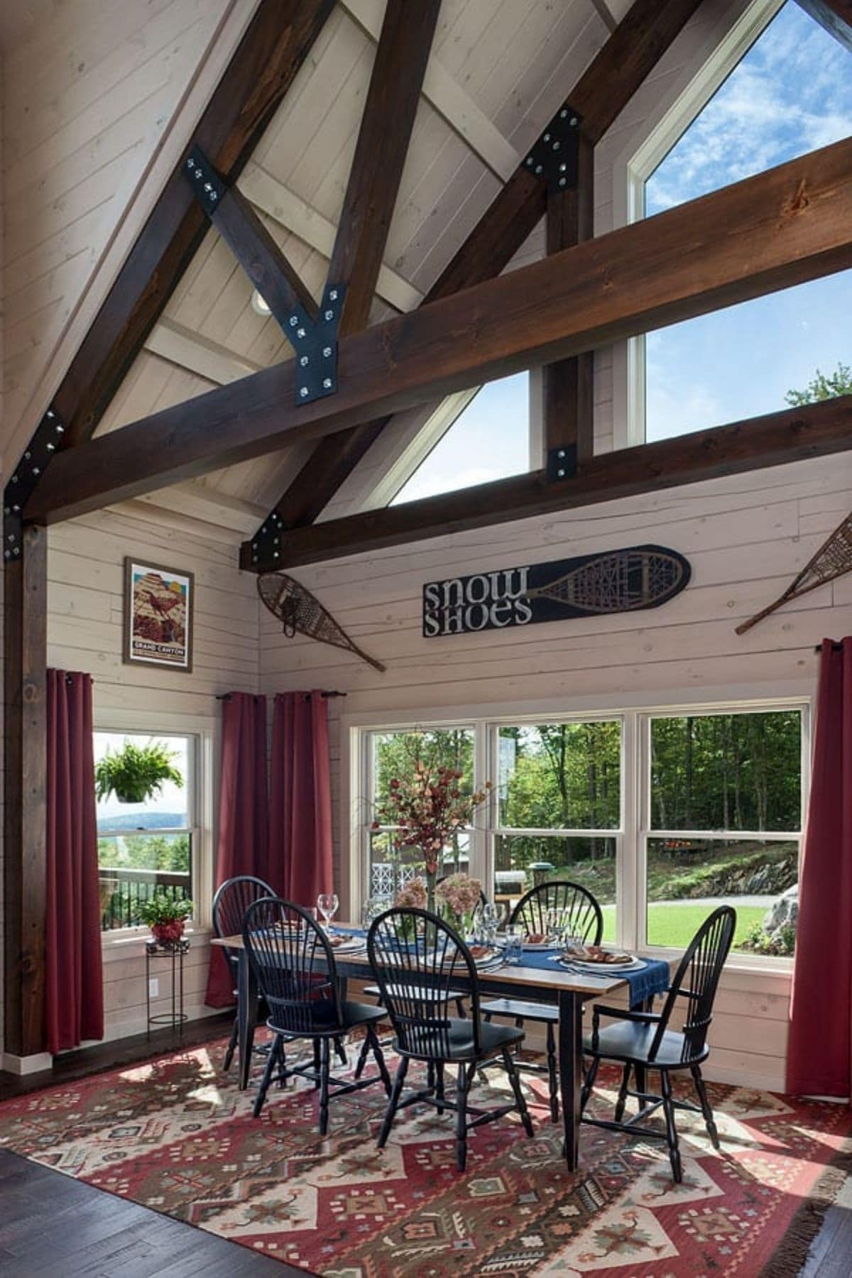 black table with chairs in dining room surrounded by windows with red curtains