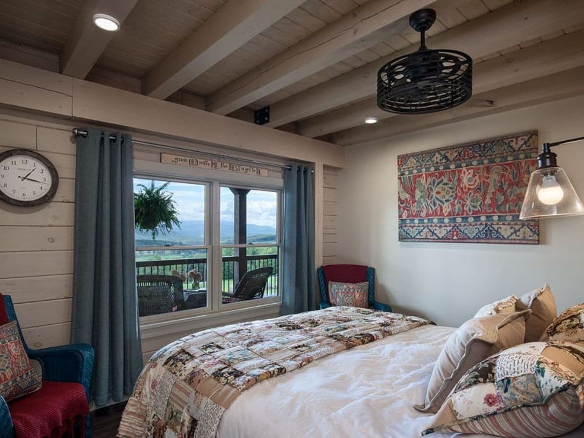 bed with white bedding in front of windows with blue curtains