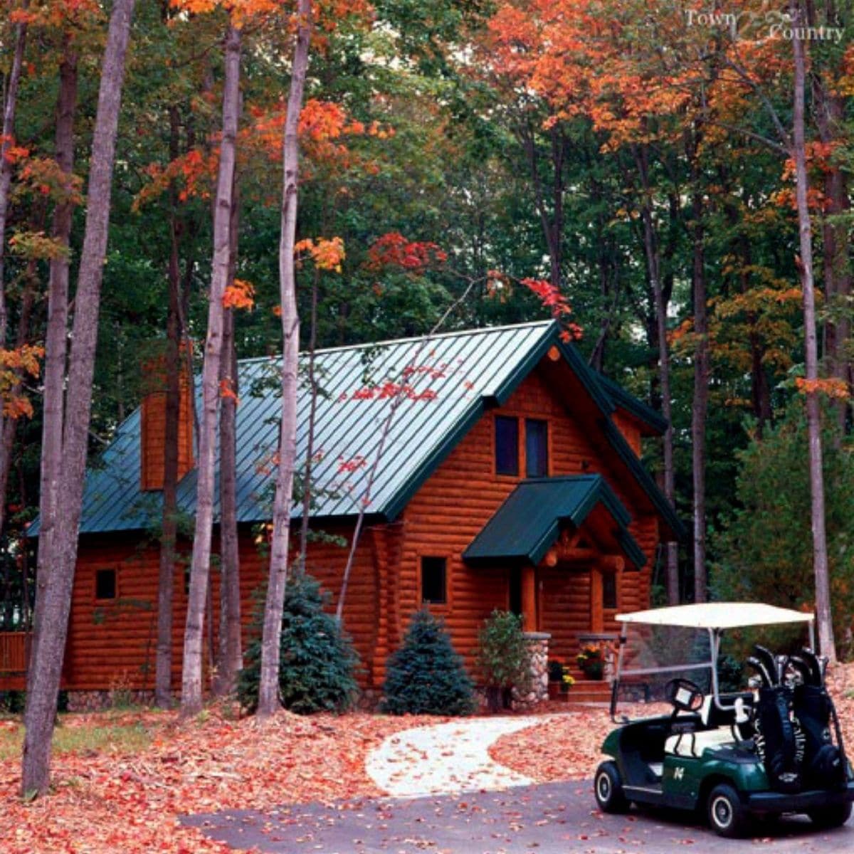 golf cart parked on drive by log cabin with green roof