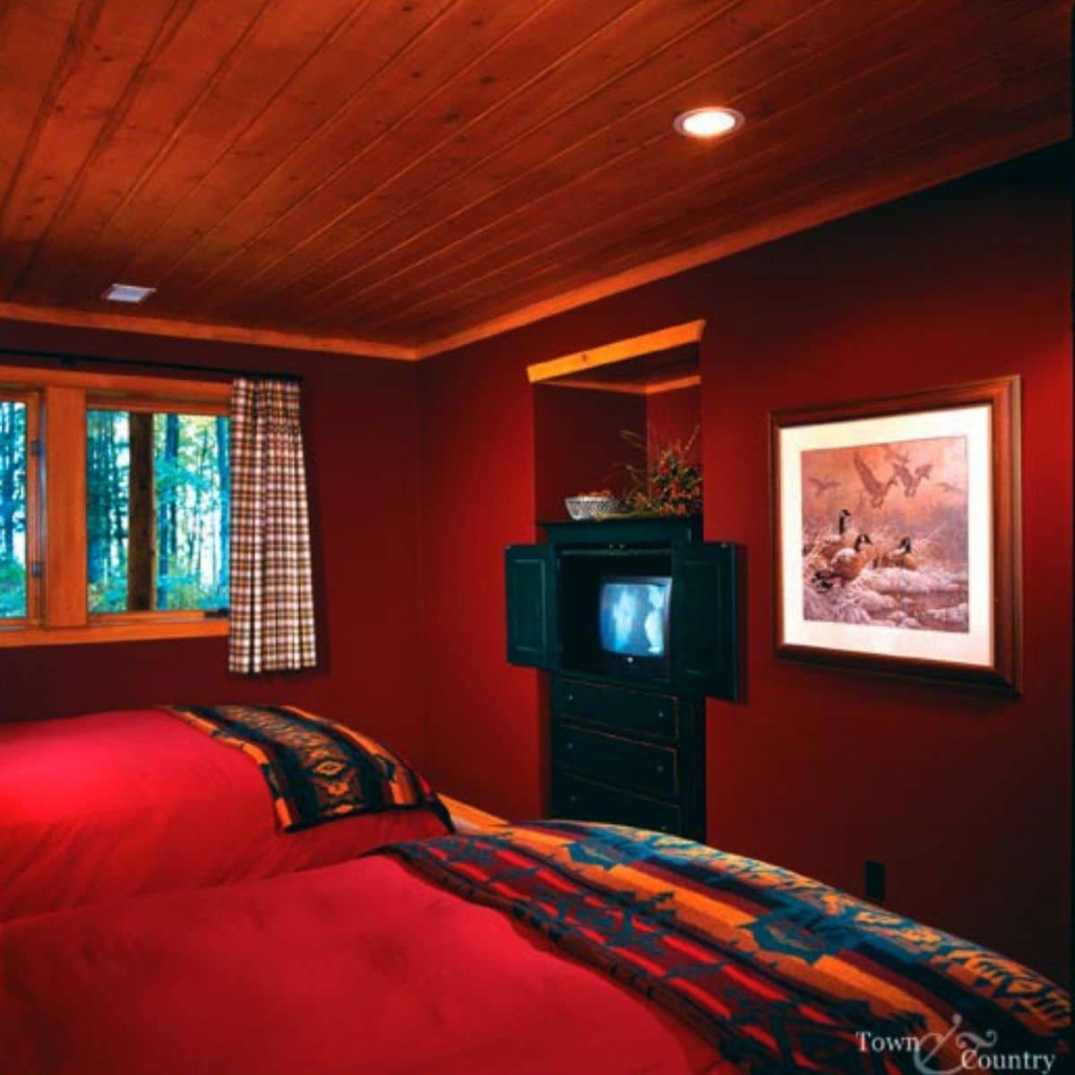red walls in bedroom with two twin beds across from black television on wall