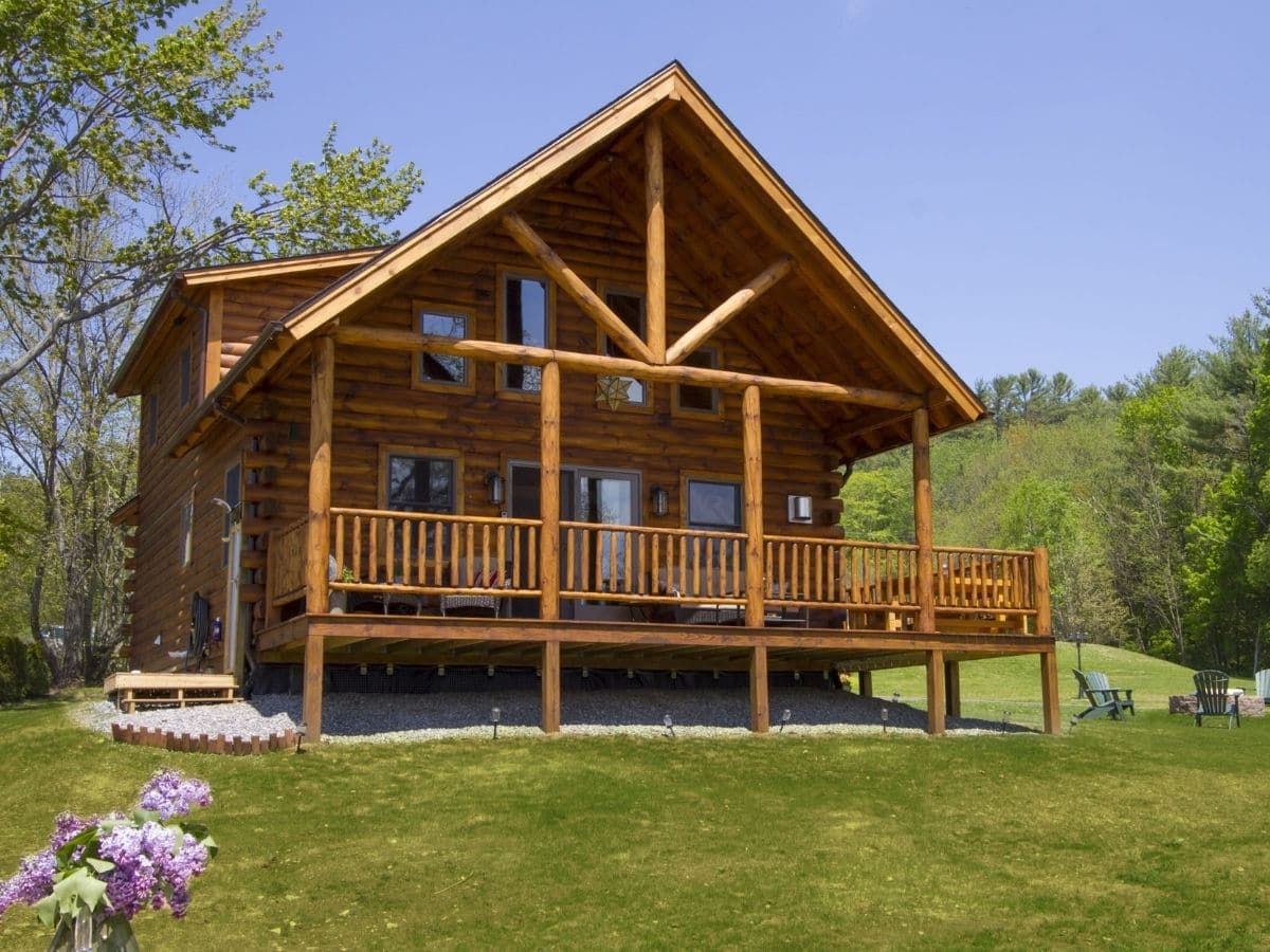 log cabin on grass with elevated front porch and awning
