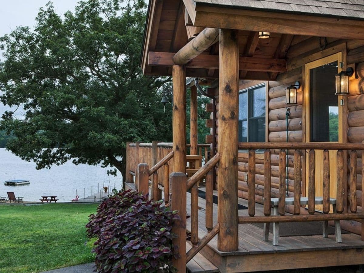 side of log cabin front porch with shrubs by steps