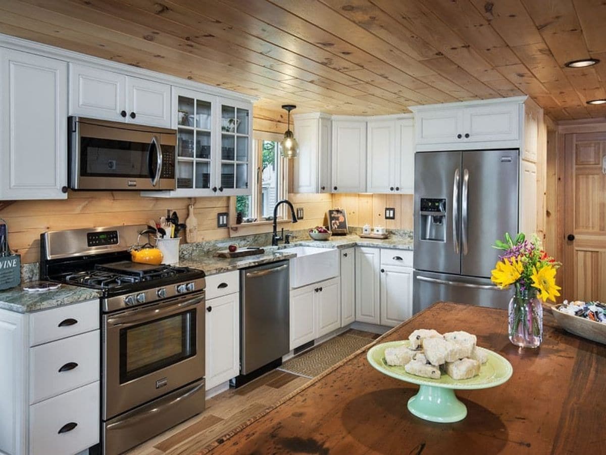 kitchen with wood island in foreground and white cabinets with stainless steel appliances in background