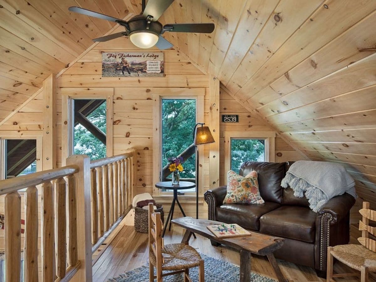 log cabin loft with door at back to patio and brown sofa in foreground