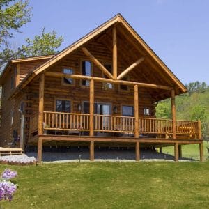 log cabin on grass with elevated front porch and awning