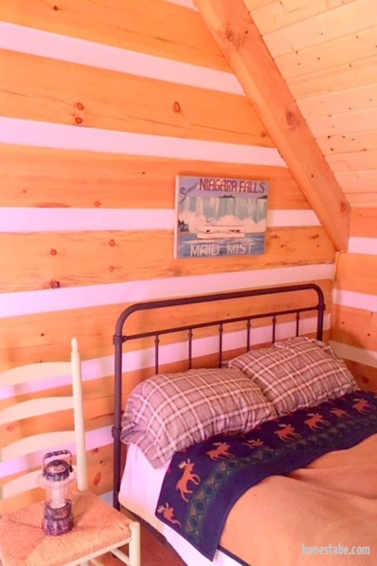 bed against log cabin wall with nightstand to left