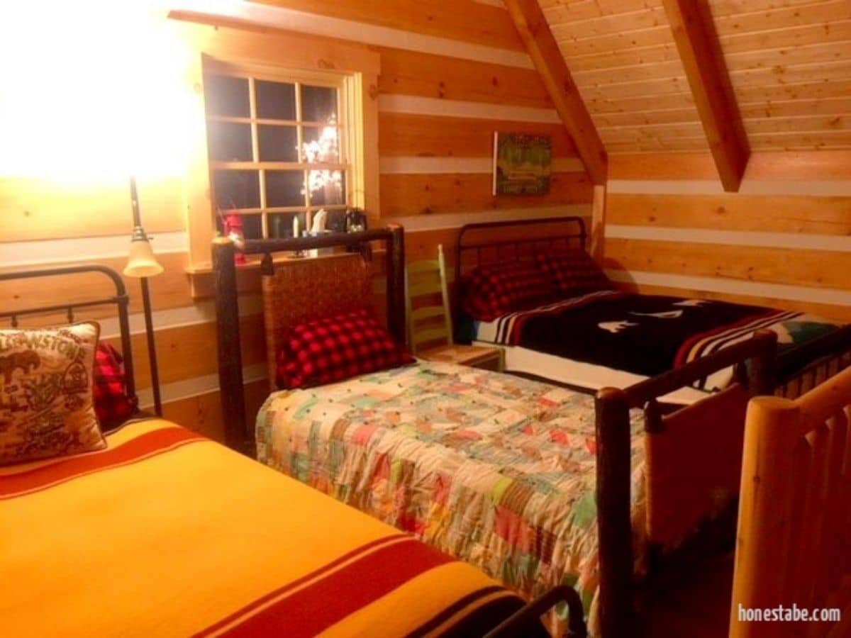 three twin beds against log cabin wall