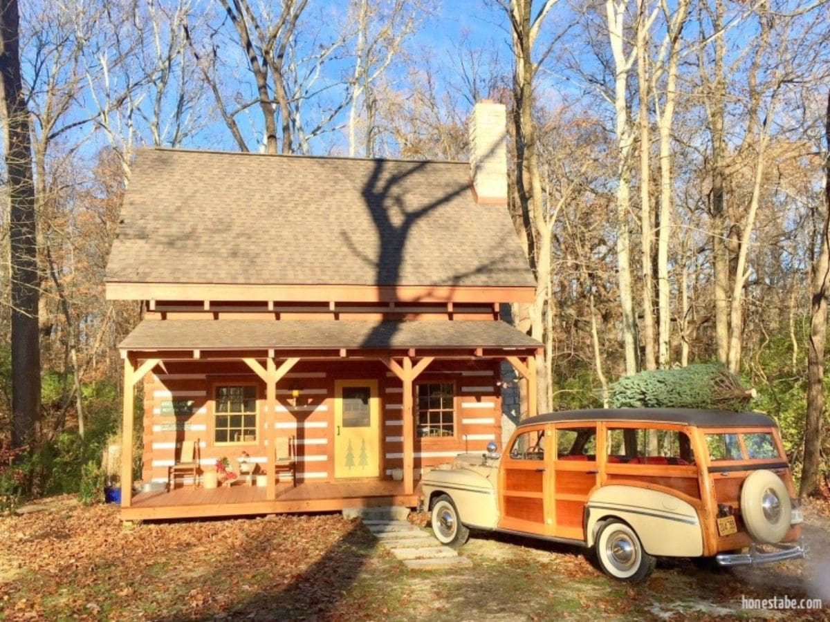 log cabin with vintage woody car with tree on top in front