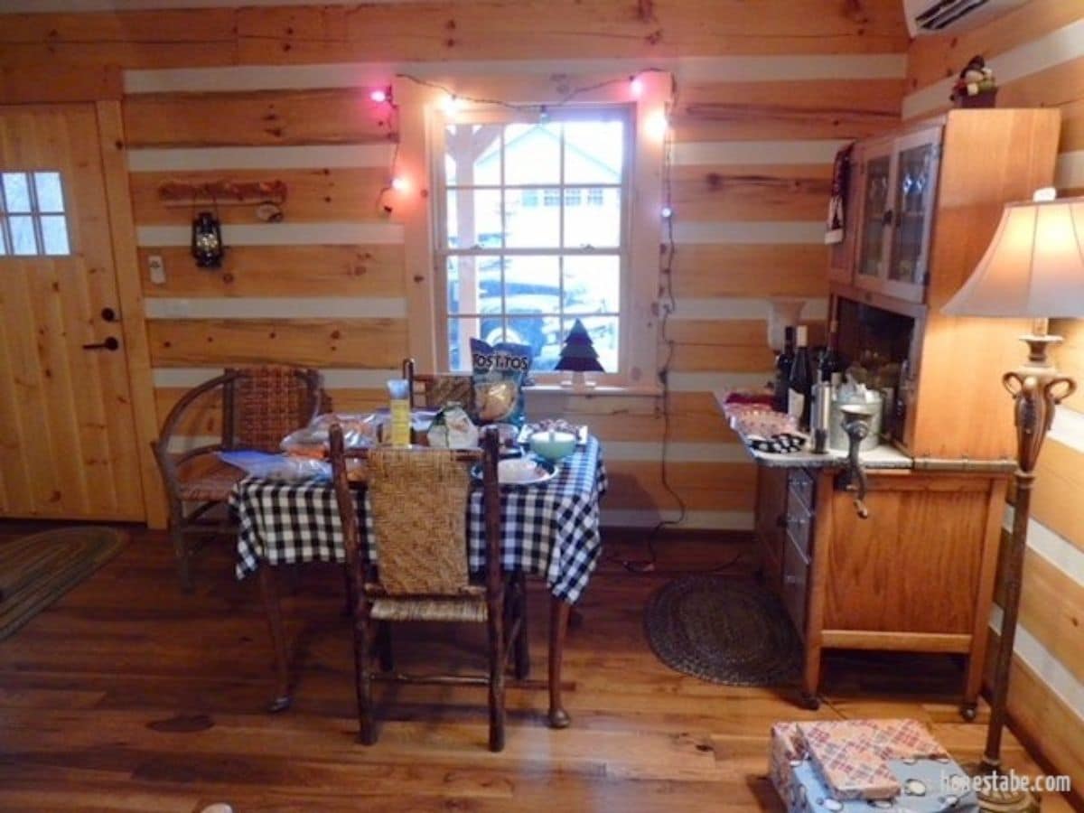 dining table in front of log cabin front window next to buffet